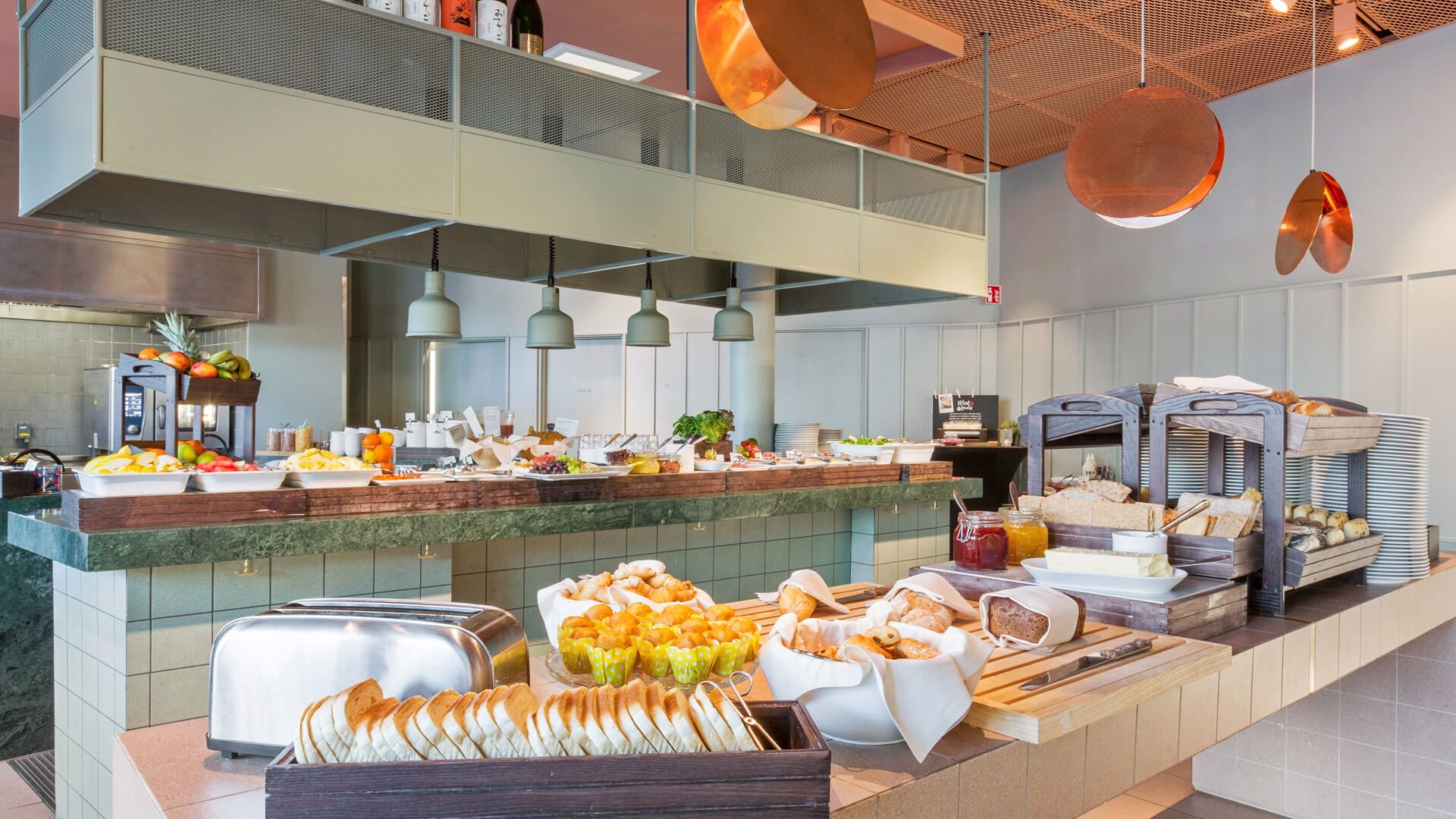 Frukostbänk med mackor, brödrost, muffins och andra godsaker.