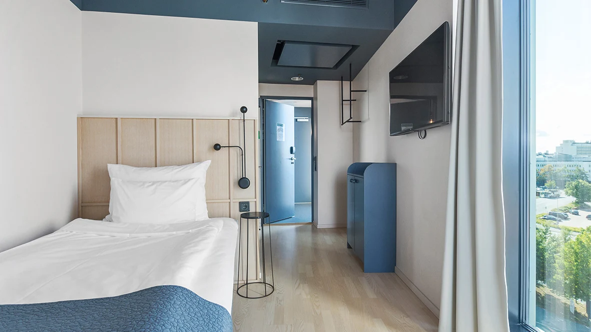 Bild på Singe Superior rum med enkelsäng och skrivbord i bild. Somrig utsikt från fönstret.  