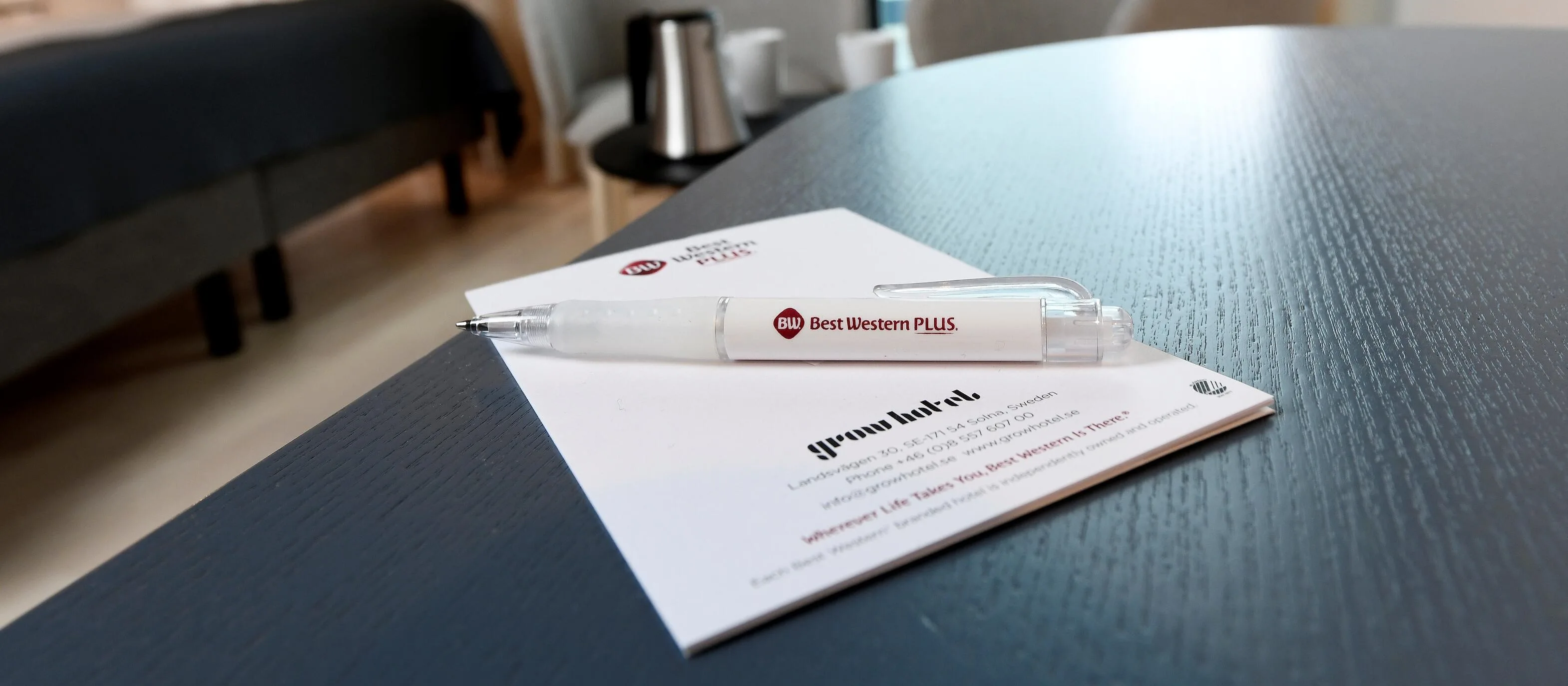 En penna och ett anteckningsblock ligger på ett bord i en konferenslokal.