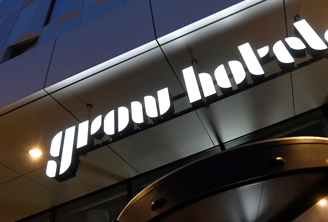 Entrén till hotellet Grow Hotel. Ljusskylt med hotellets logotyp ovanför en svängdörr.